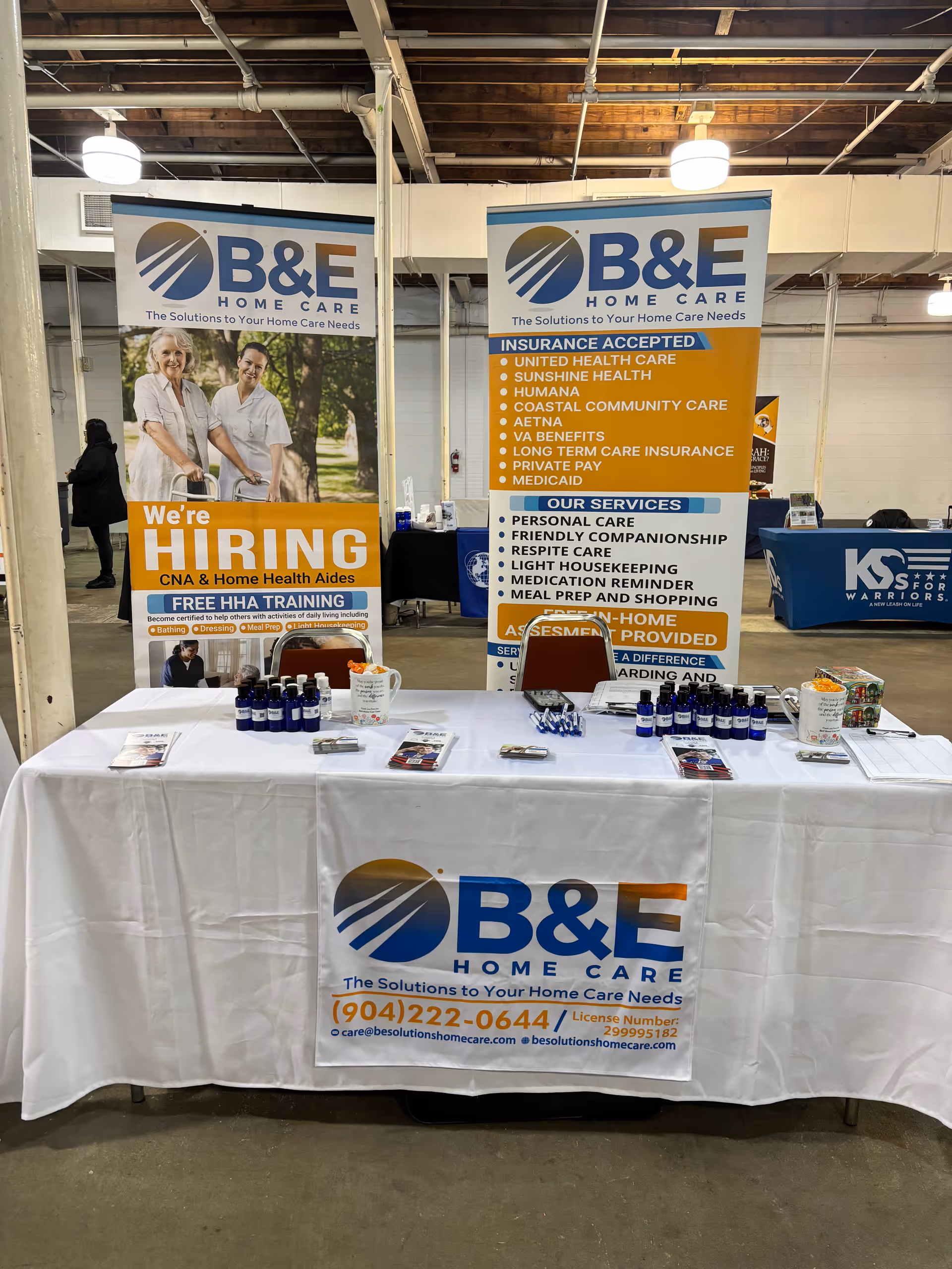 Indoor booth display for B&E Home Care banners and table at a trade show.