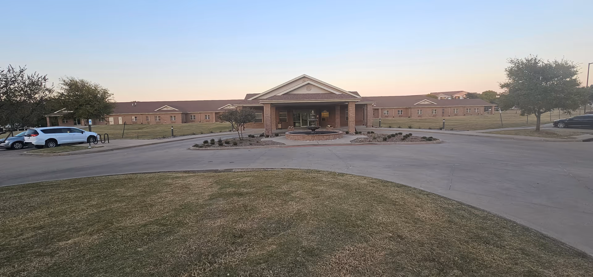 A brick senior living facility with a circular driveway and landscaped entrance.