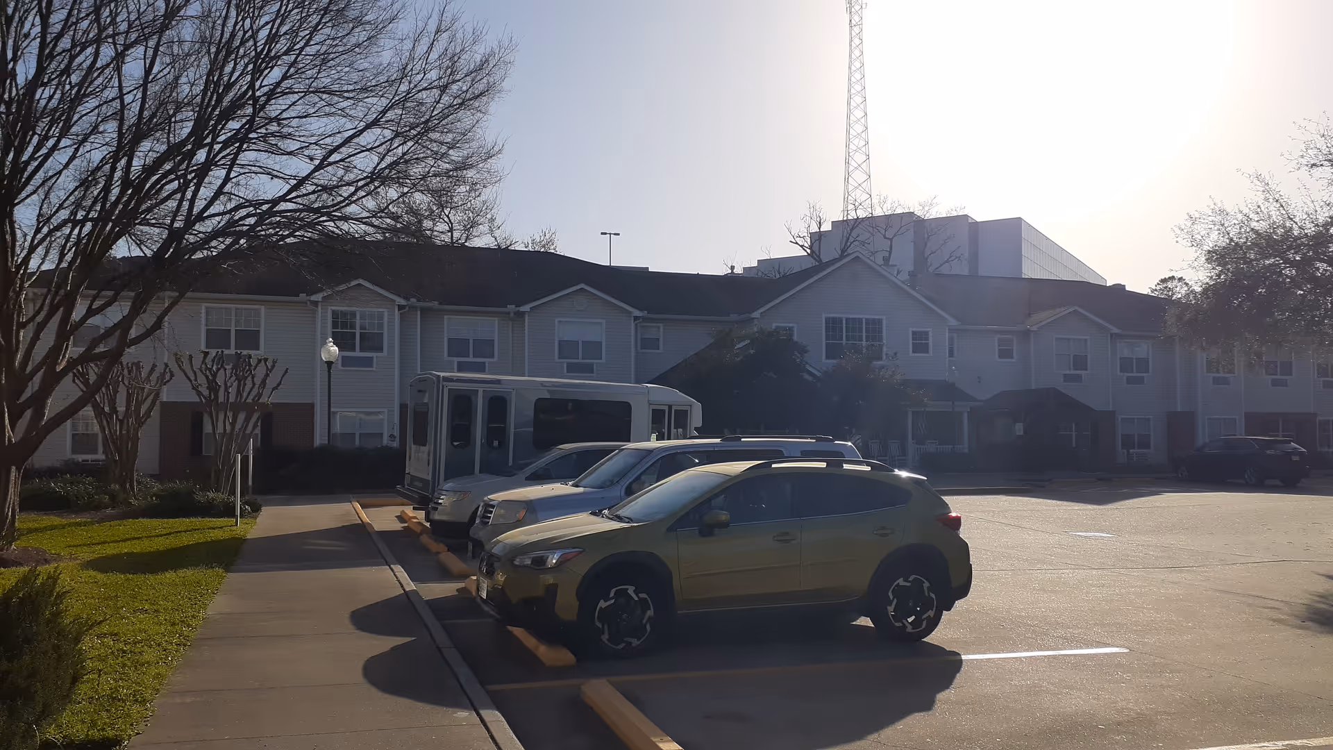 Exterior view of Brookdale the Heights senior living facility with parked cars and a bus.
