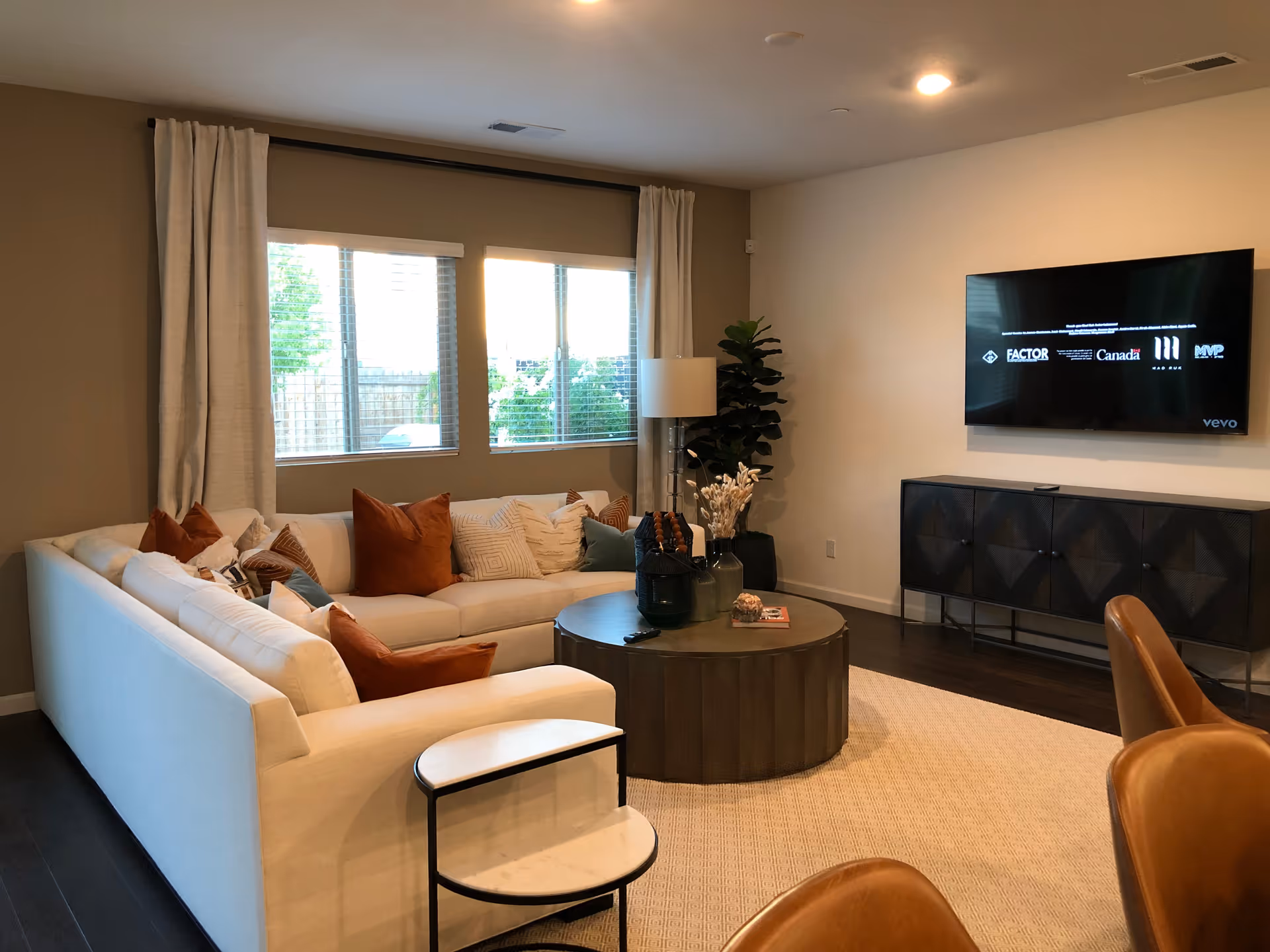 Bright living room with a white sectional, round coffee table, and wall-mounted TV.