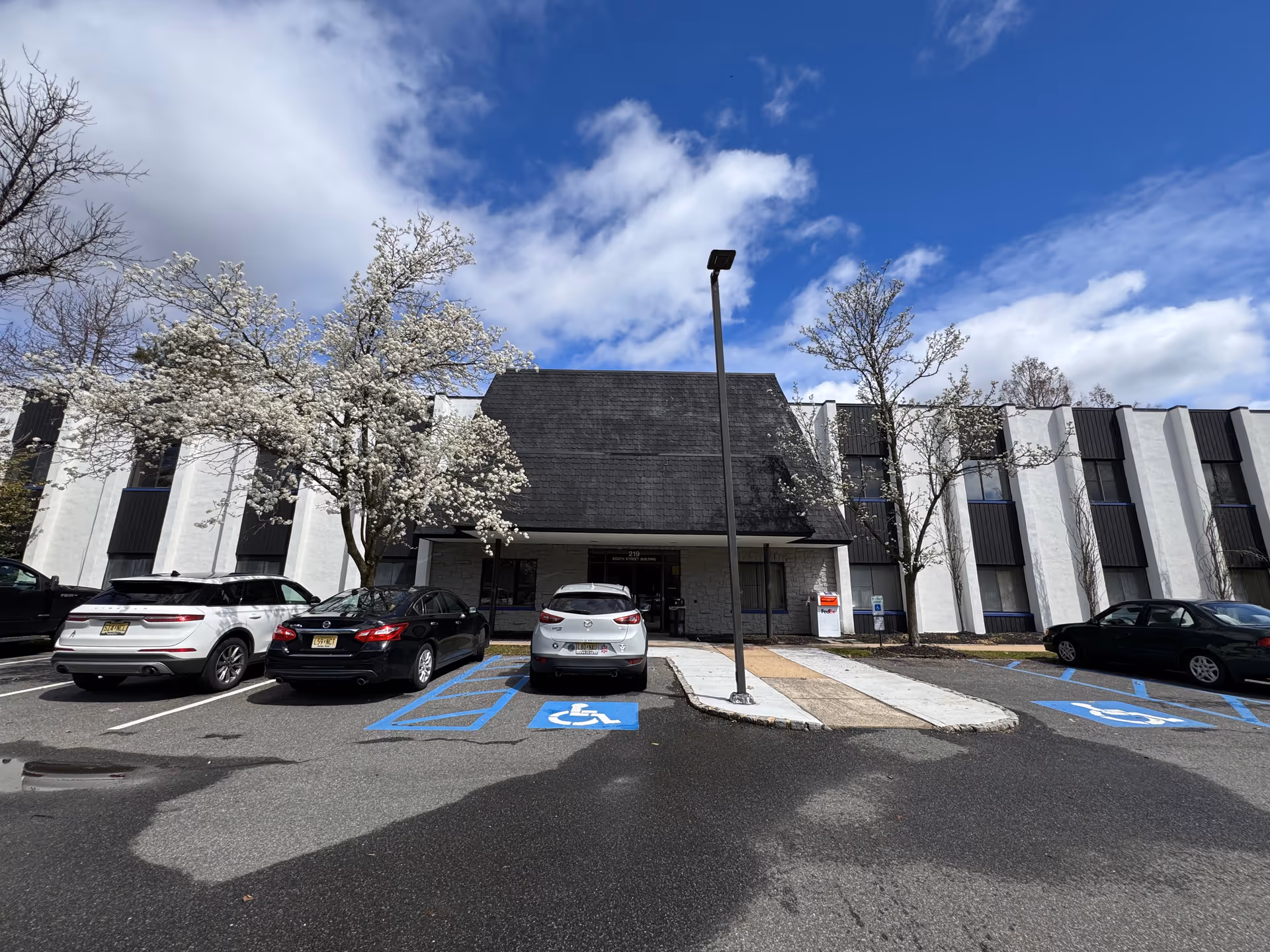 Facade of A & J Majestic Care building with parking spaces and blooming trees in front.