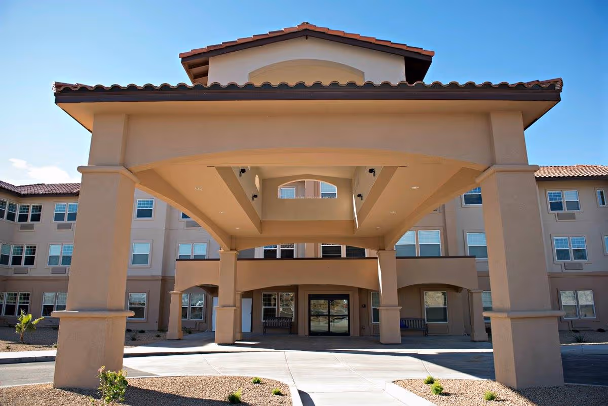 Front view of a tan senior living facility with a large covered entrance canopy.