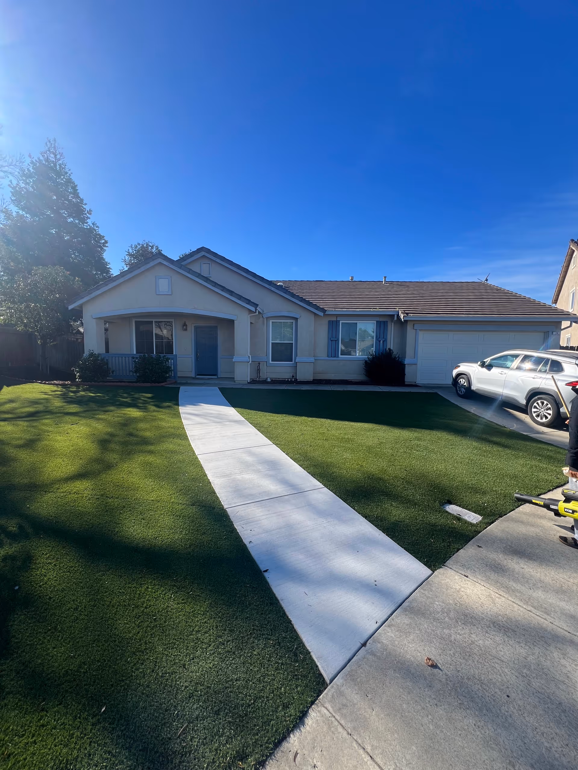 Front view of a single-story house with a curved white walkway across a green lawn.