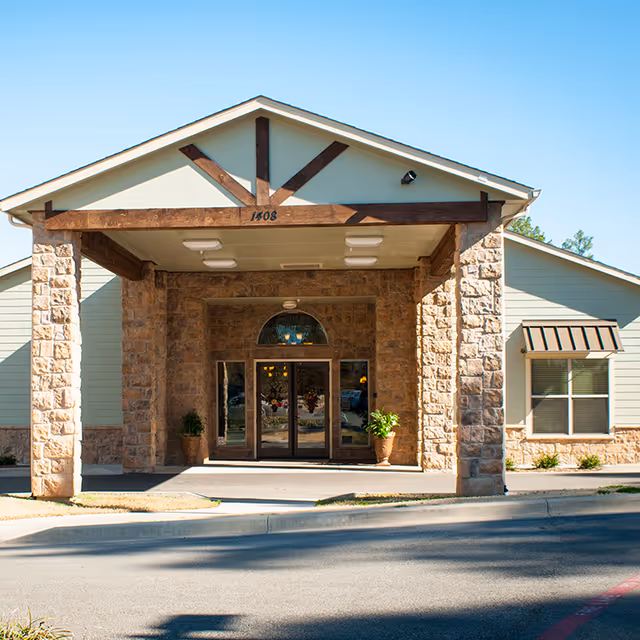 Entrance of Heartis Longview senior living facility with stone pillars and glass doors.