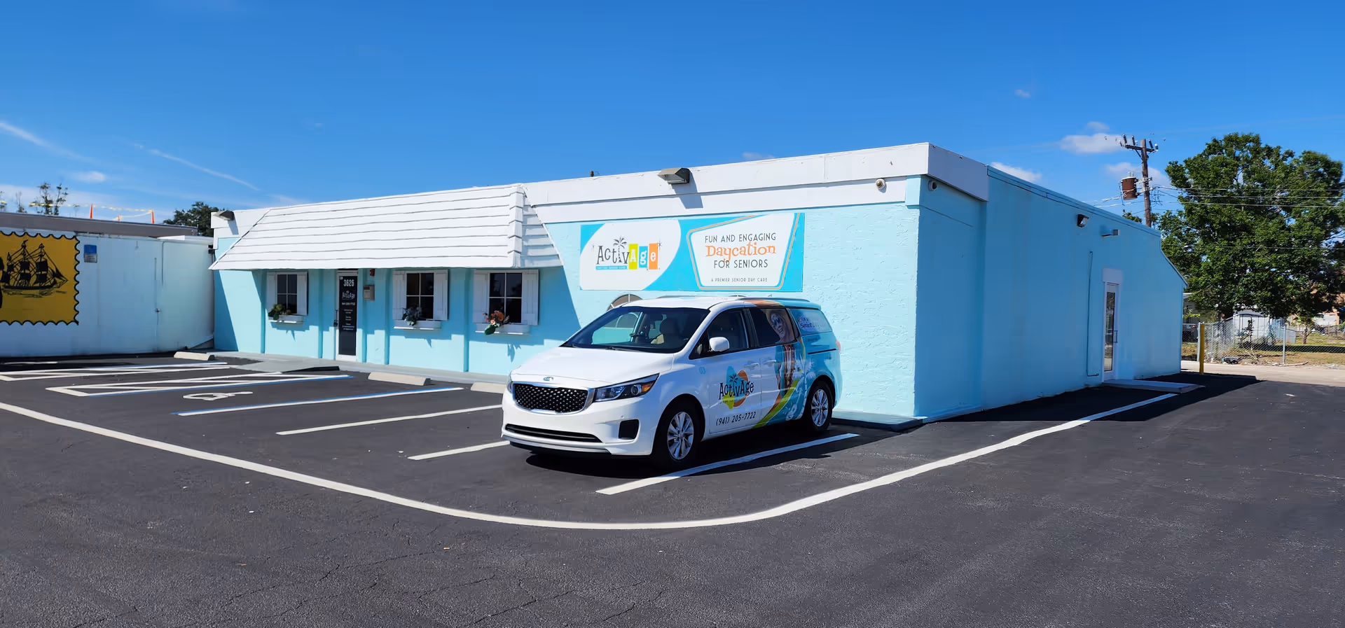 Light blue, single-story building with a parking lot and a white van parked in front.