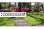 Pathway winds through green lawn and trees toward Covenant Towers sign.