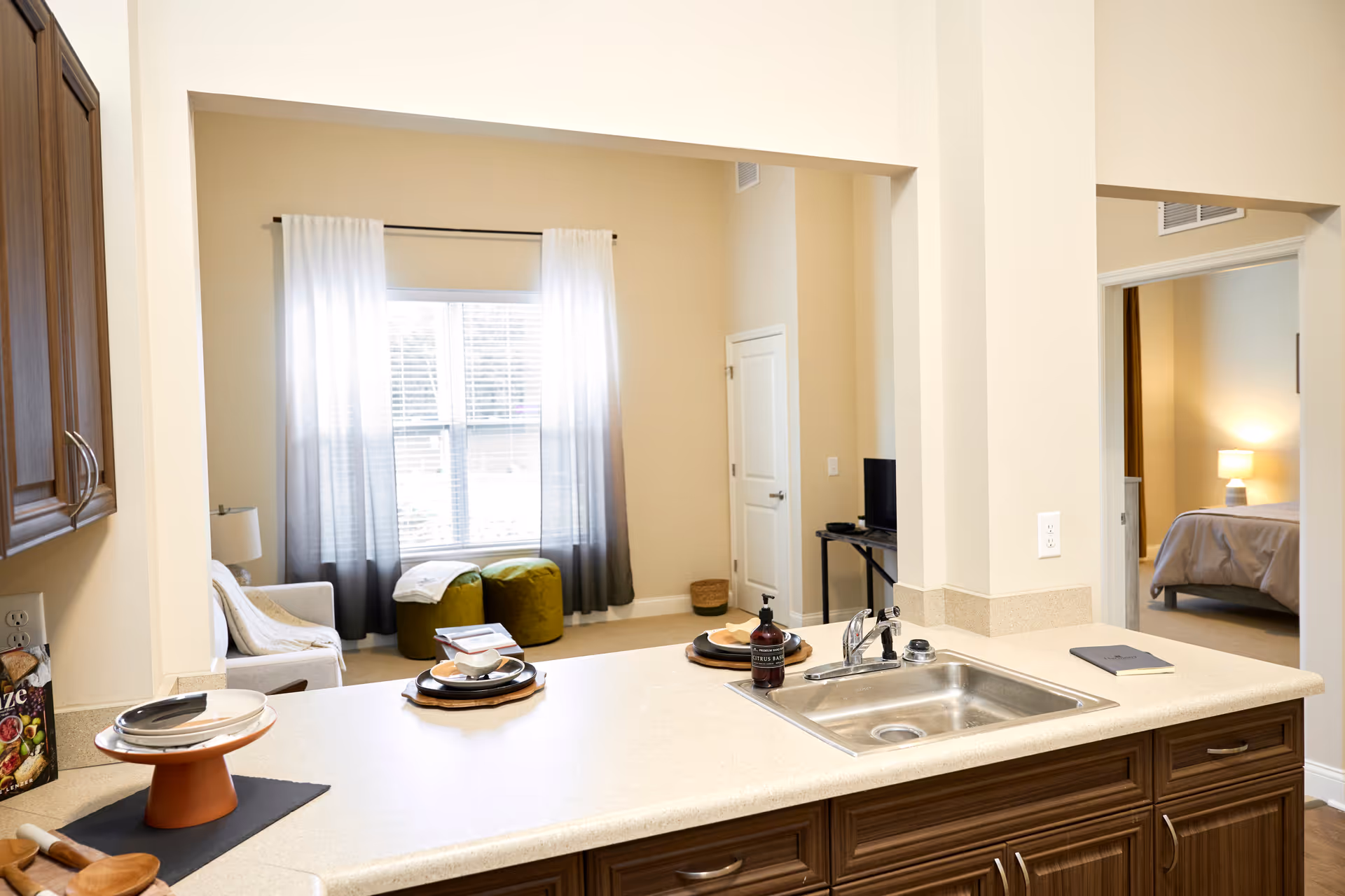 Open-concept kitchen with sink and counter, overlooking living area and bedroom.