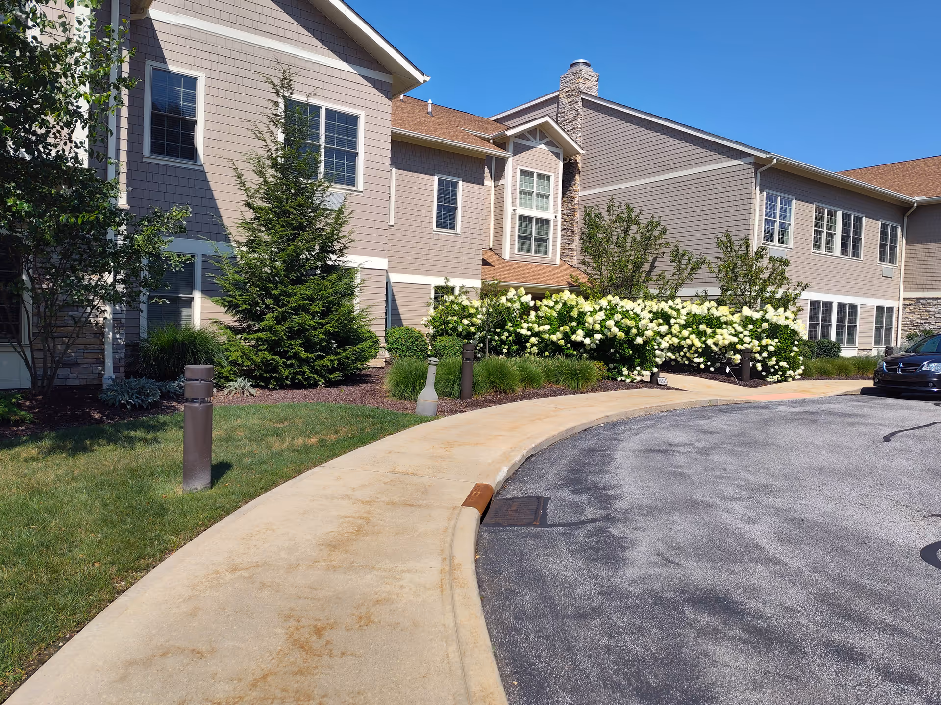 Front exterior view of Shurmer Place with landscaped shrubs and a curved walkway.