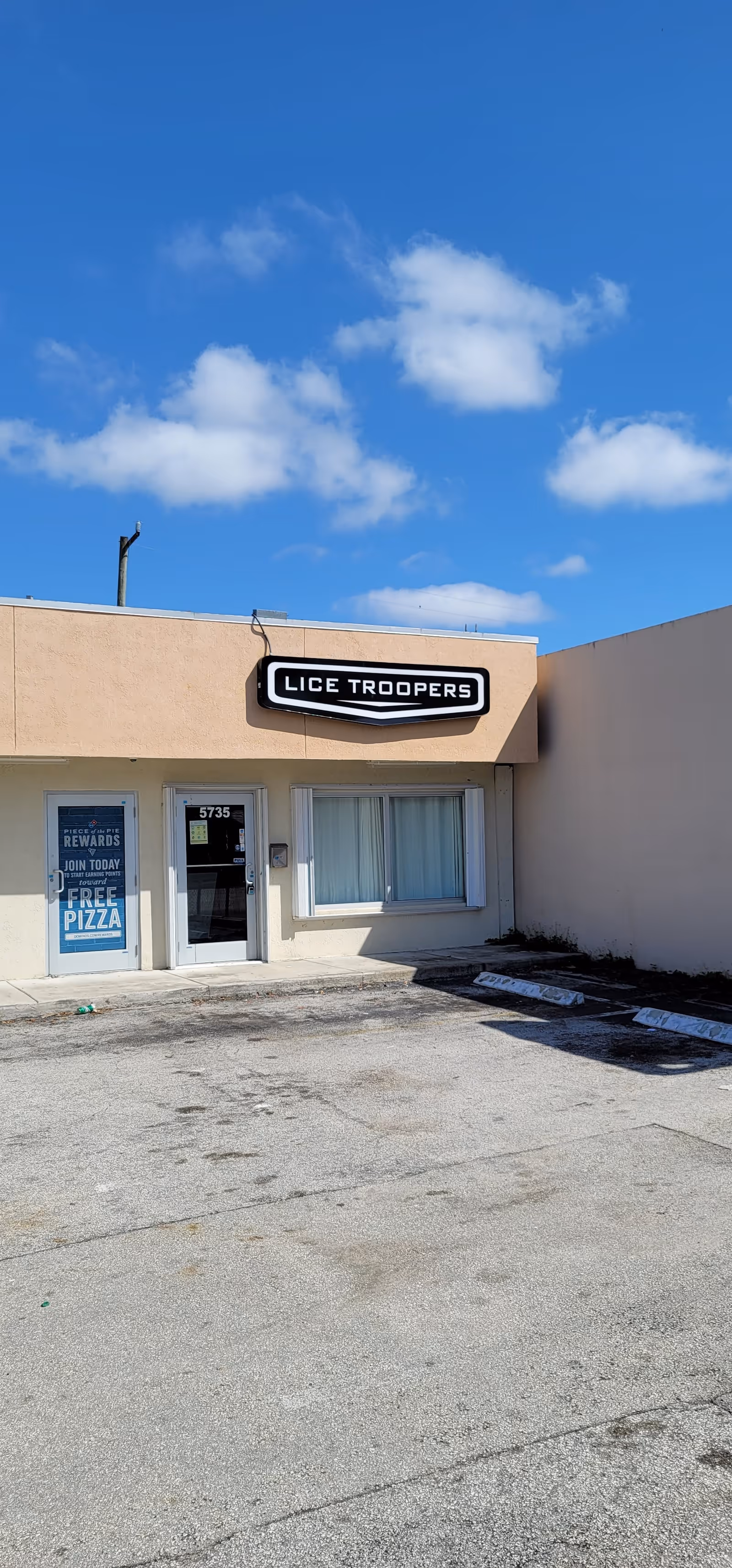 Front exterior view of Lice Troopers storefront with sign and empty parking lot.