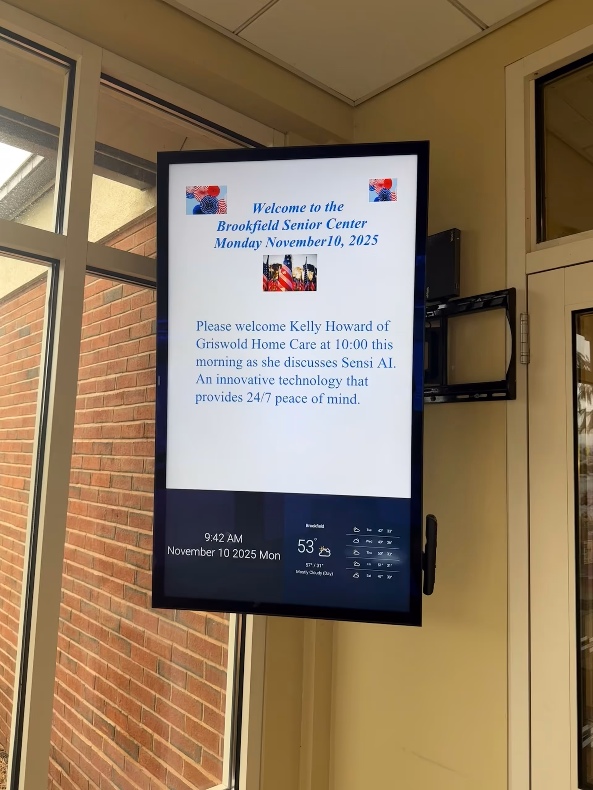 Indoor lobby features a tall digital display welcoming visitors and mentioning Griswold Home Care.