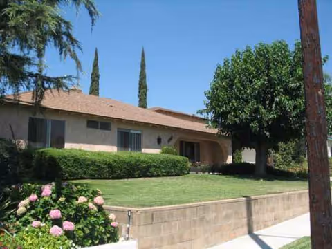 Exterior view of Genesis Manor with a manicured lawn and trees.