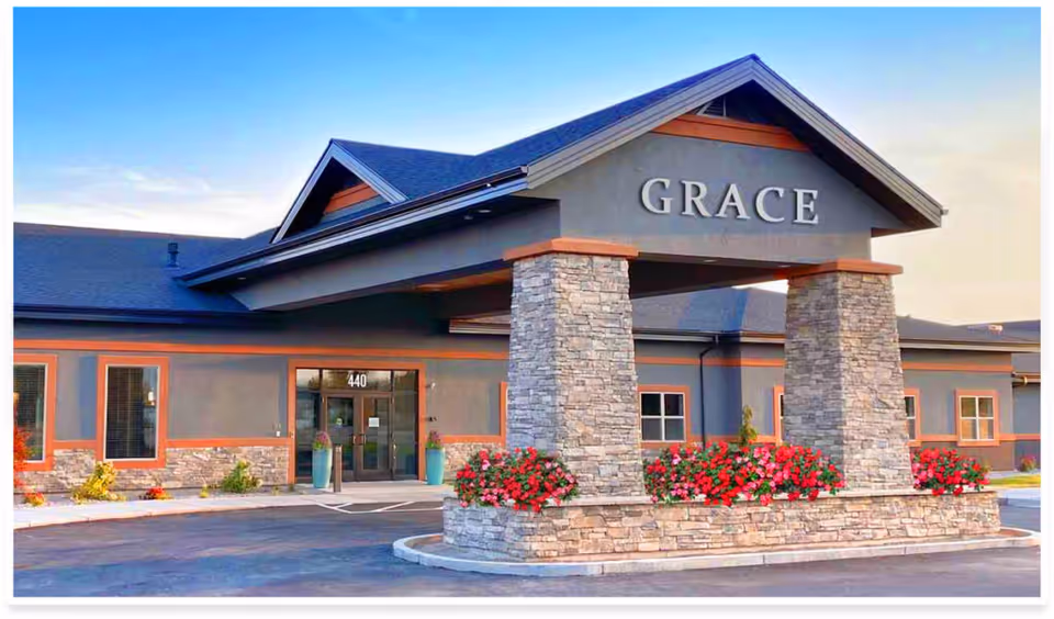 Exterior view of Grace Assisted Living entrance with stone pillars and flowers.