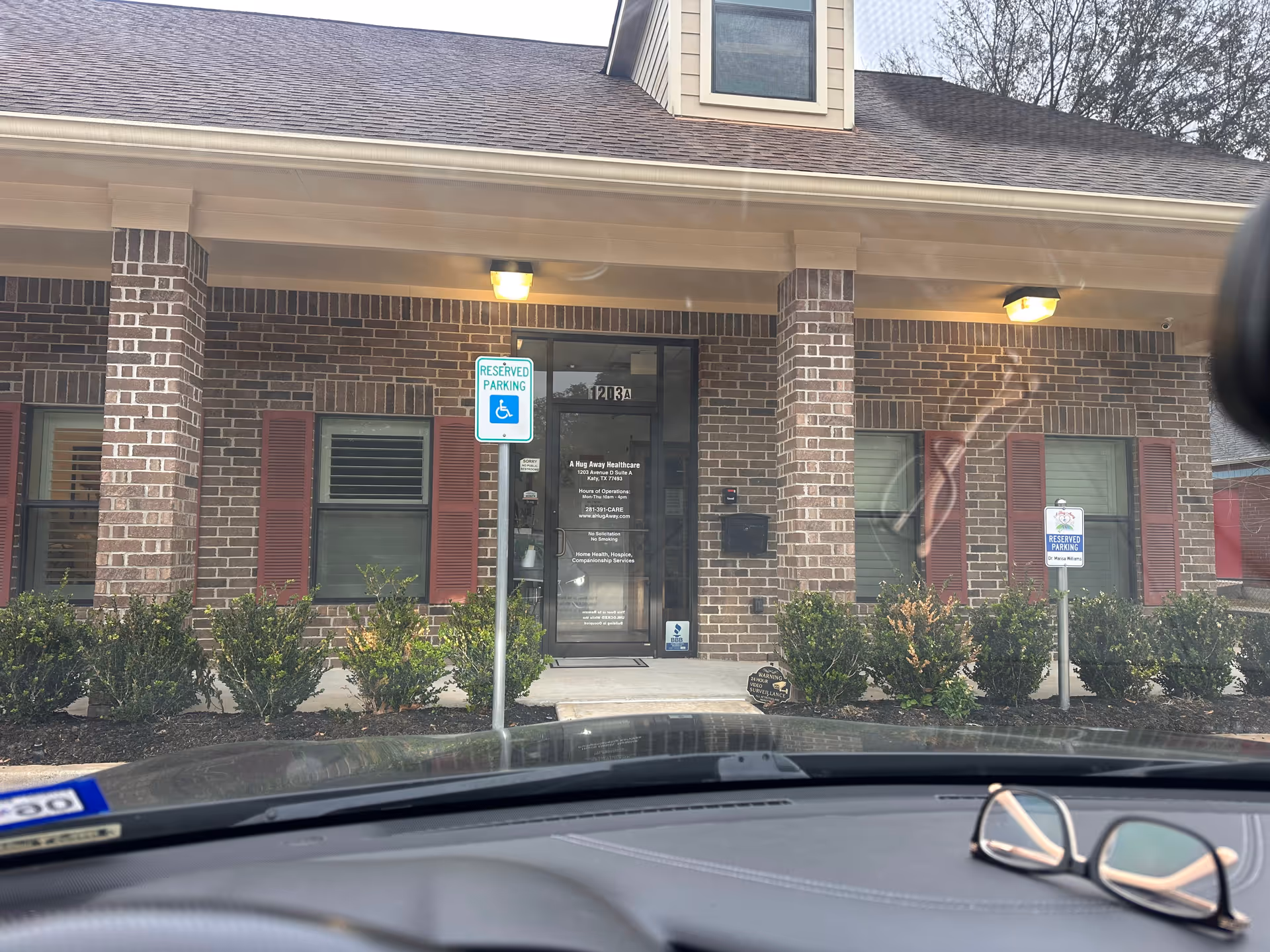 Front entrance of a brick building with handicap parking signs and shrubs.