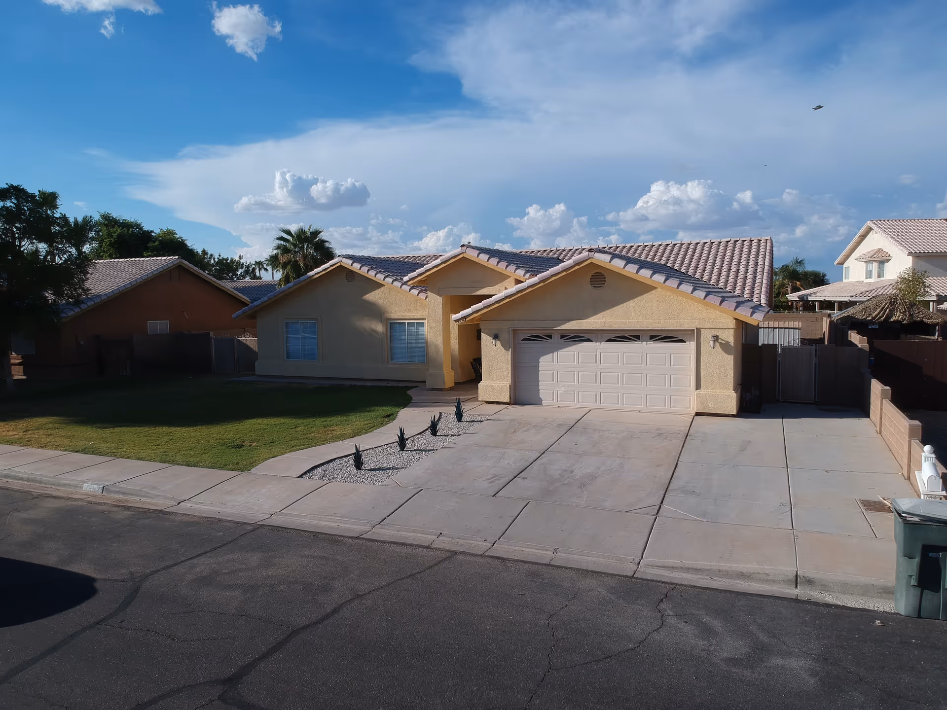 Suburban beige single-story house with a two-car garage, driveway, and front lawn.