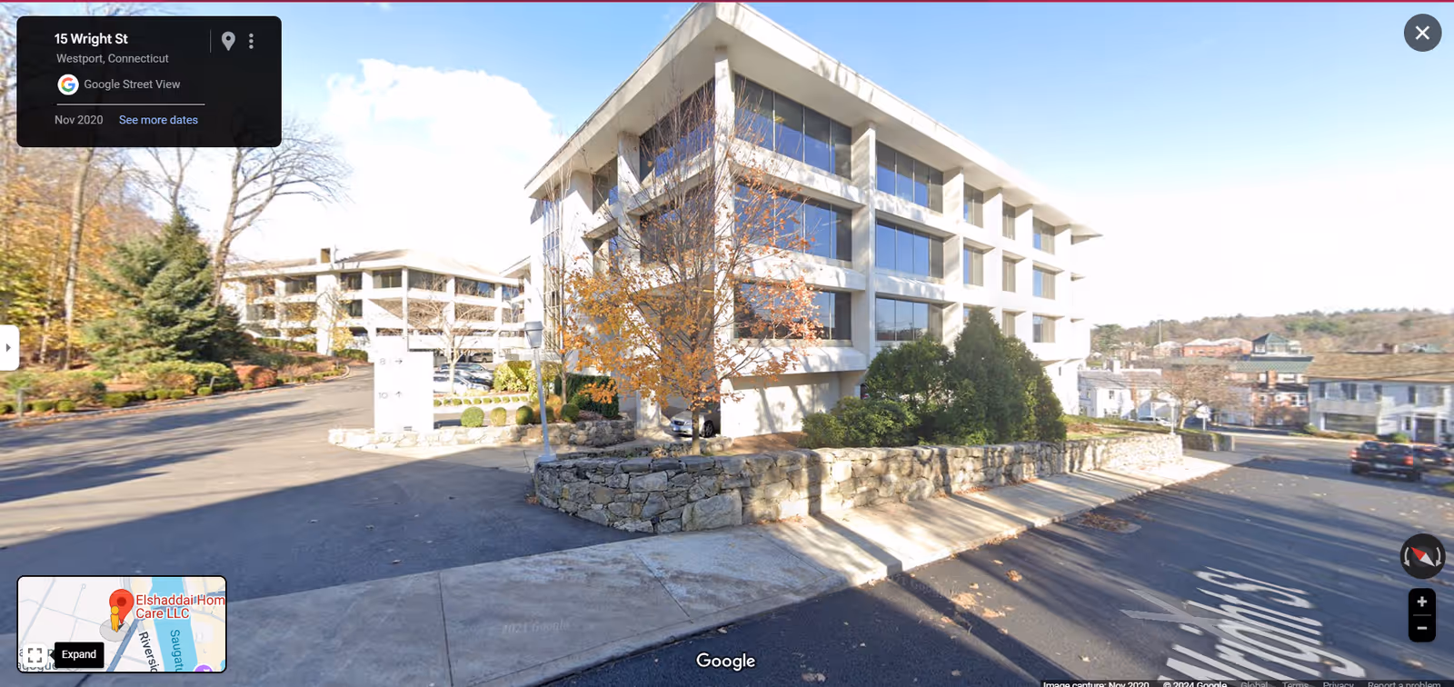 Exterior view of a modern senior living building front with parking and trees.