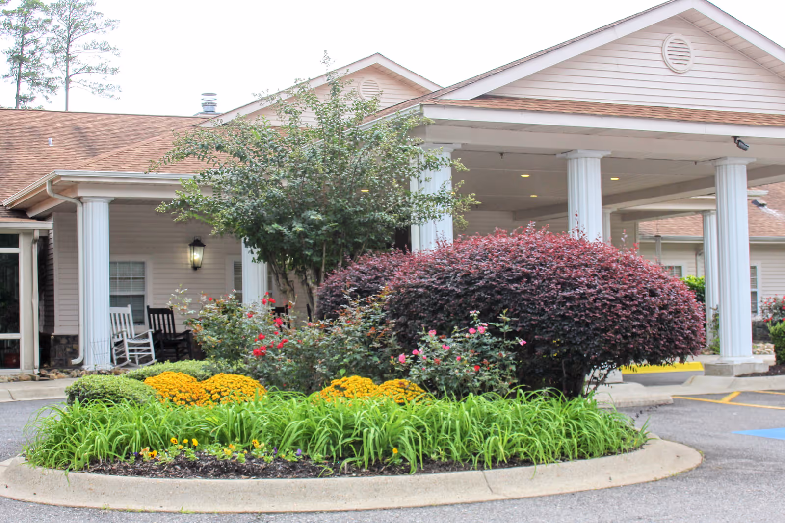 Exterior view of Garrett Woods Senior Living Community entrance with columns and landscaped garden.