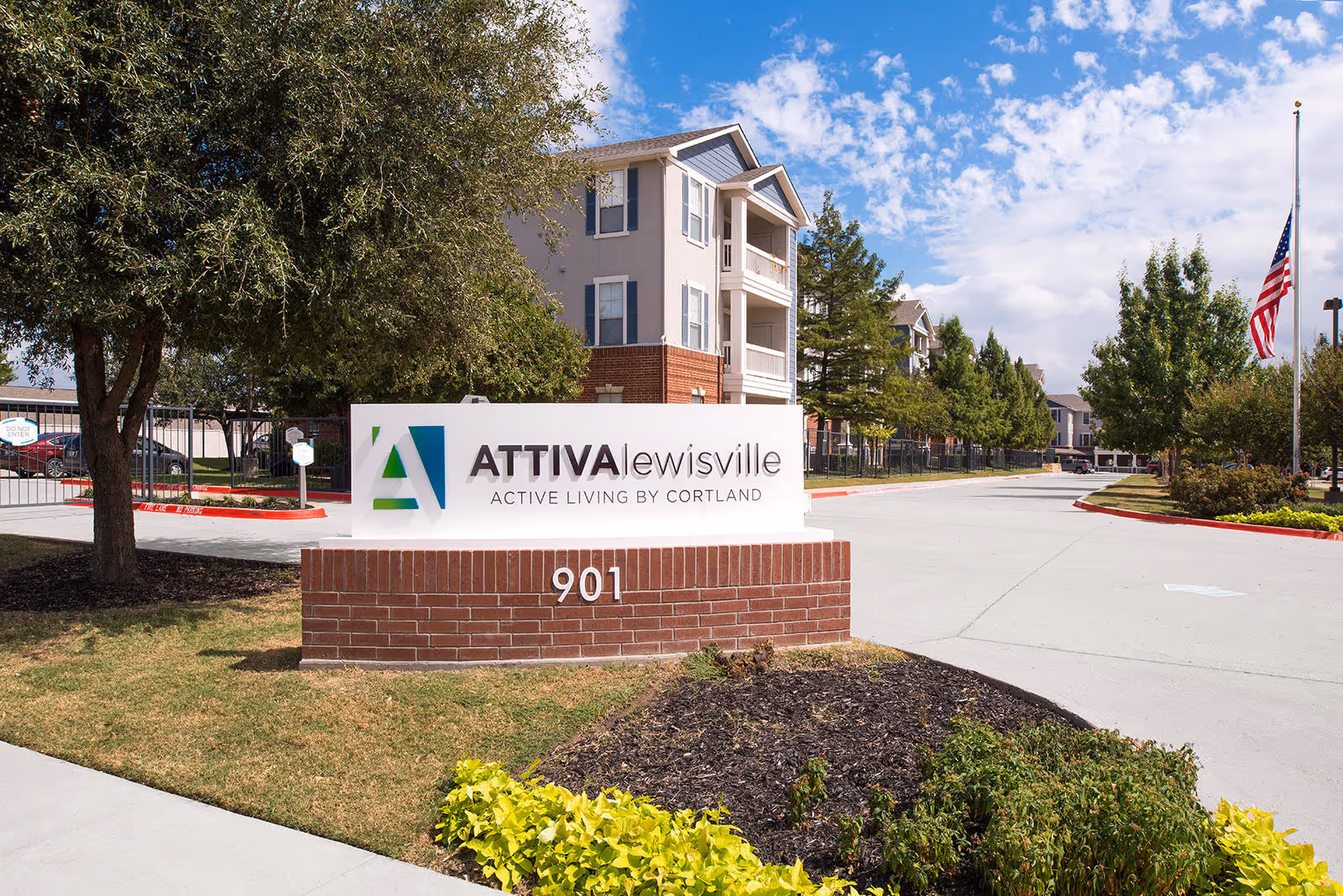 Exterior view of senior living facility entrance with a sign and brick landscaping in the foreground