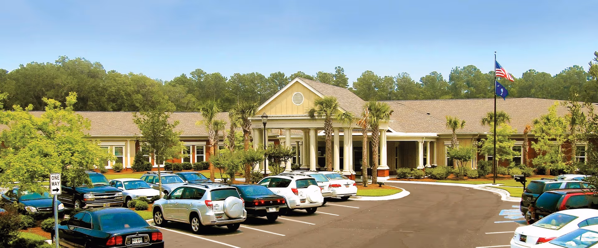 Exterior view of The Palmettos of Bluffton with a parking lot and entrance.