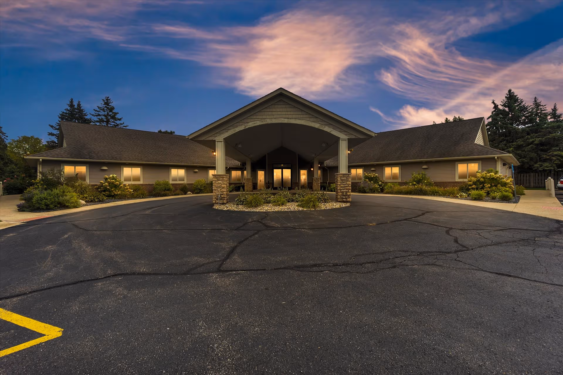 Single-story senior care facility with a covered front entrance, circular drive, and landscaped surroundings.