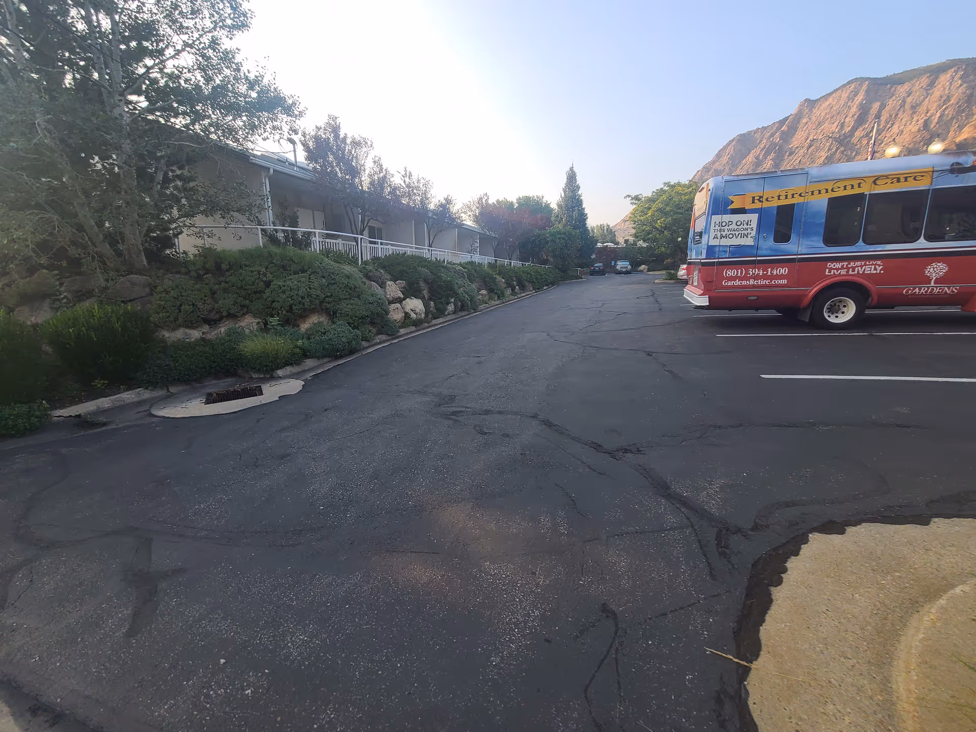 Parking lot in front of Gardens Assisted Living with a red retirement bus on the right.