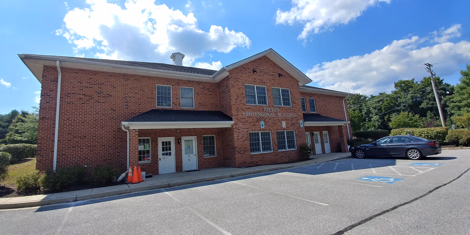 Brick two-story building with parked cars under a blue sky.