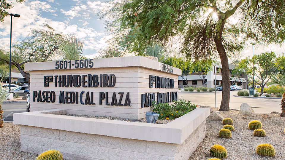 Stone sign reads Thunderbird Paseo Medical Plaza with desert landscaping and trees.
