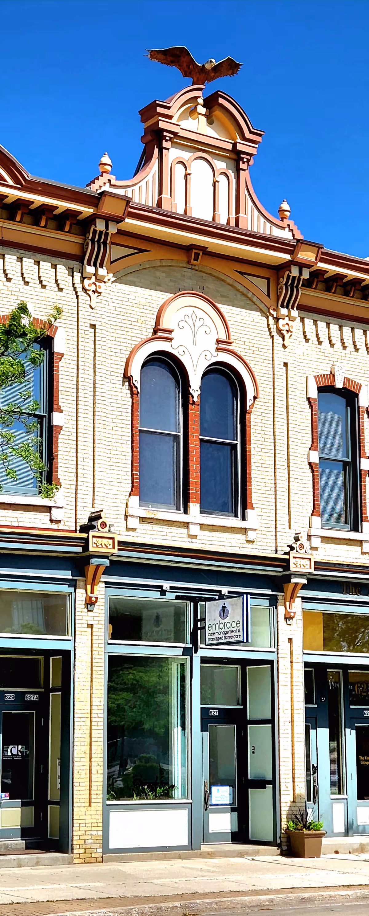 Ornate brick building facade with arched windows and Embrace signage.