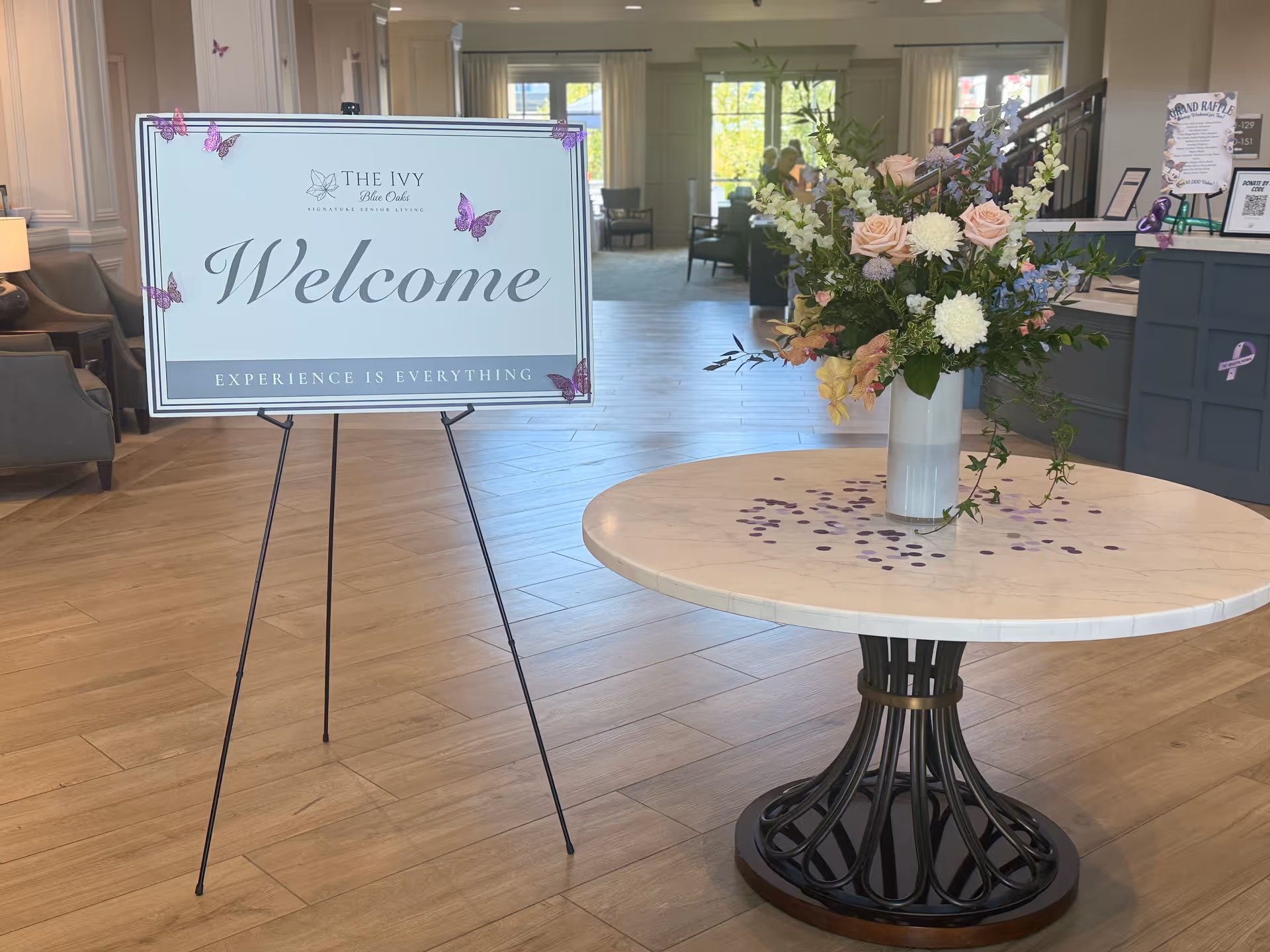 Lobby interior with a welcome sign, round table bouquet, and seating in the background.