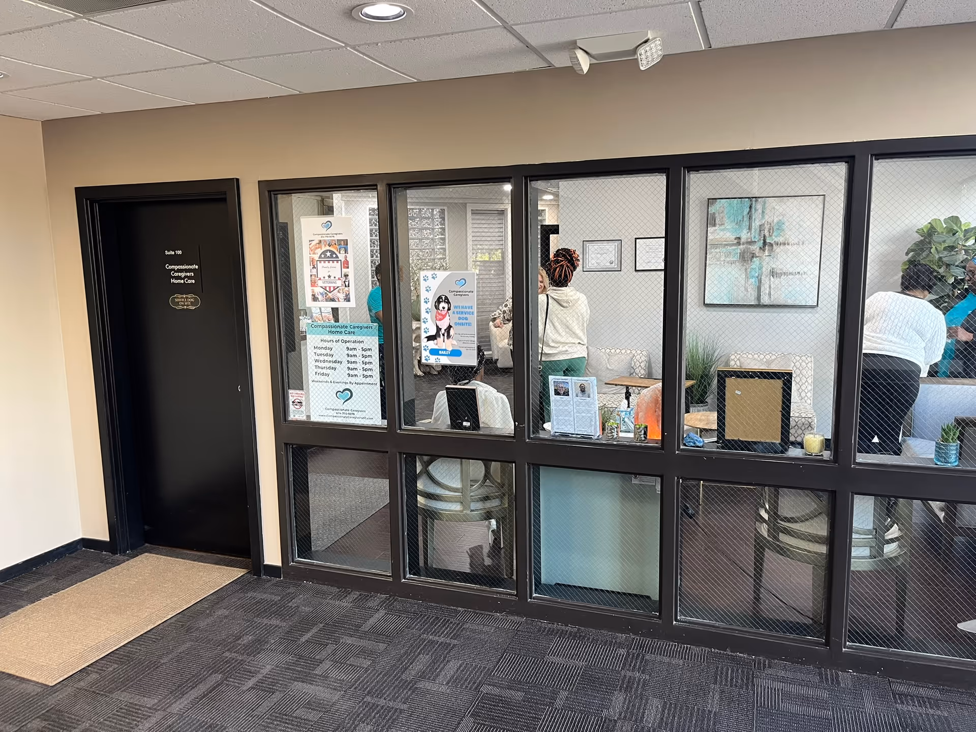 Interior lobby with glass partitions, posters, and staff inside a care facility reception area.