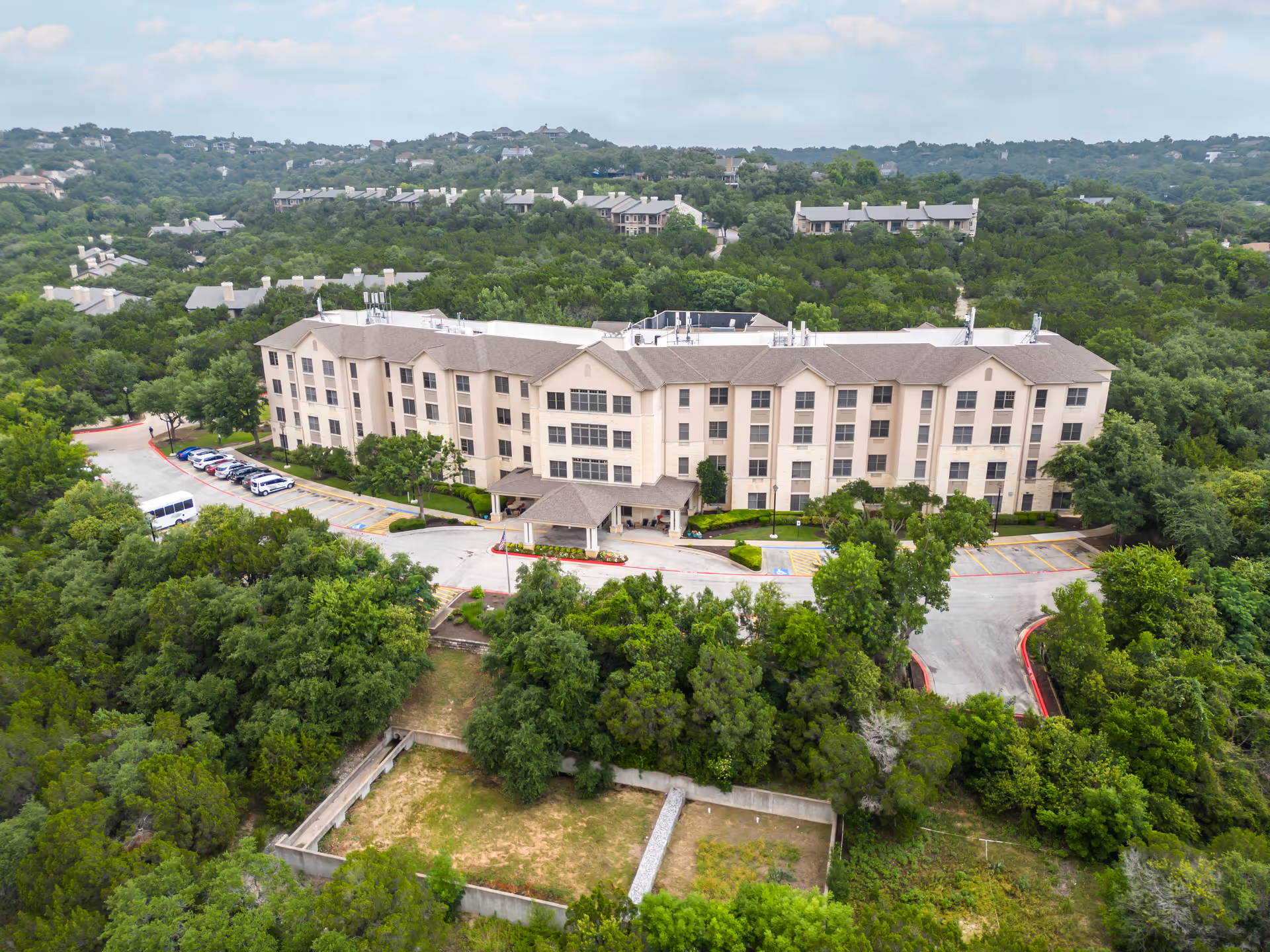 Aerial view of a large Brookdale Northwest Hills senior living building amid trees.