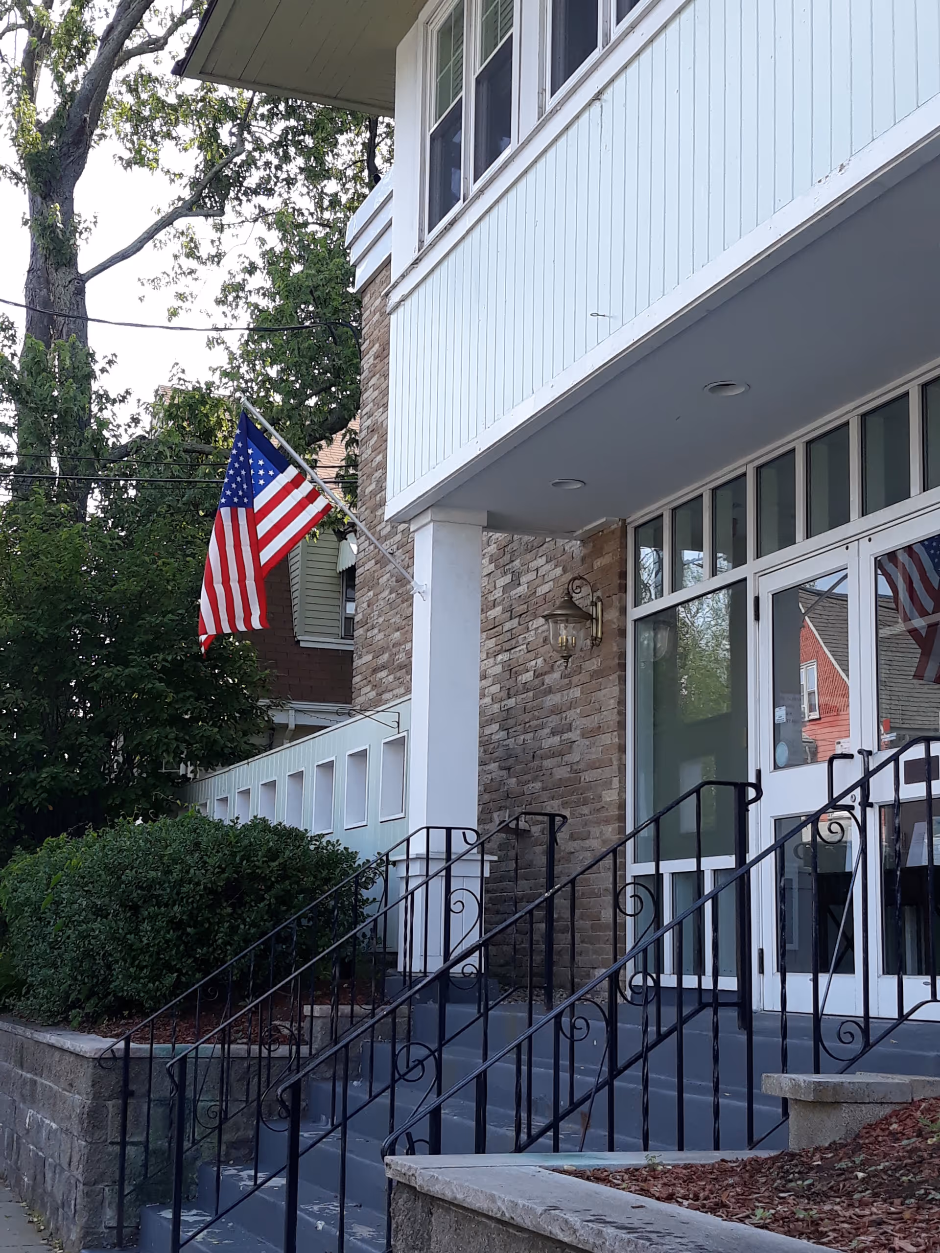 Front entrance of Abbott Skilled Nursing and Rehabilitation Center with stairs and flag.