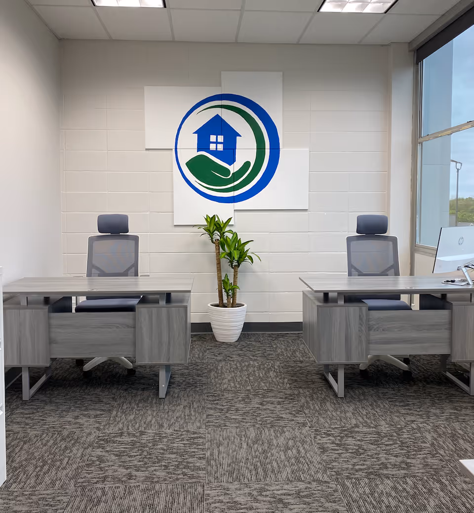 A modern reception area with two desks, a plant, and a circular logo on the wall.