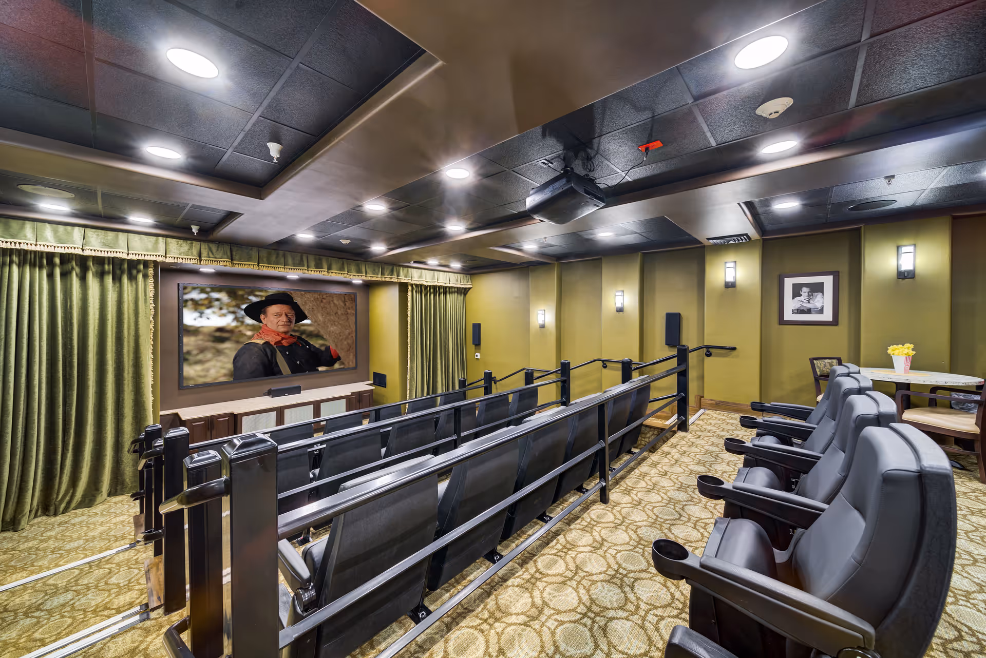 Indoor theater in a senior living facility with rows of seats facing a large screen.
