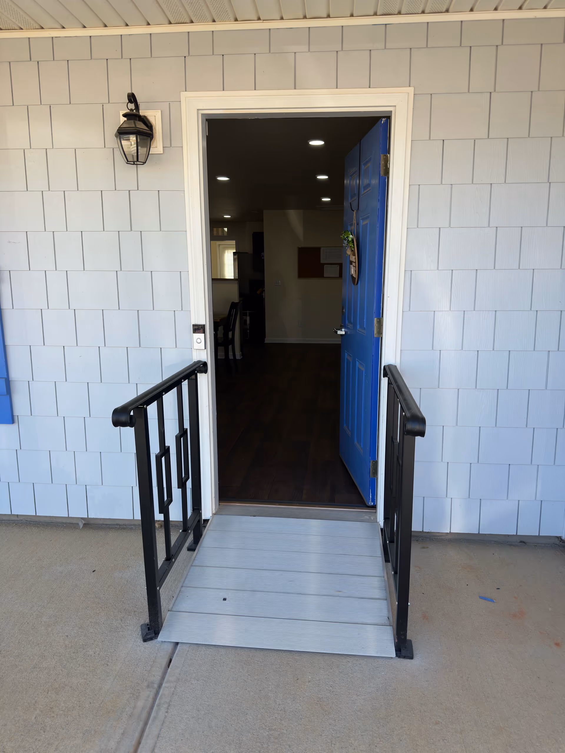 Open blue front door leads into hallway of a senior living facility.