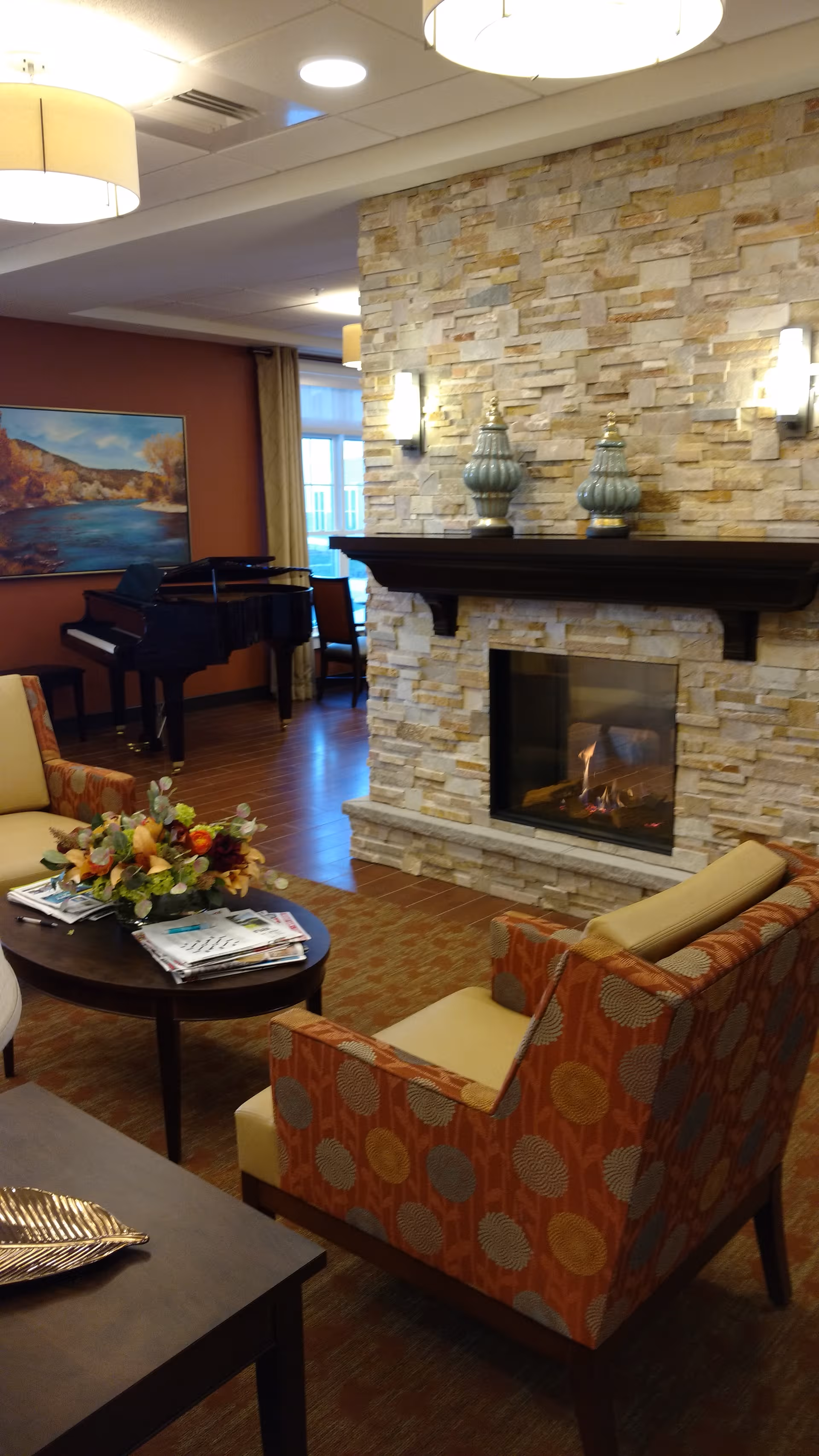 Cozy lounge area with a stone fireplace, seating, and a piano.
