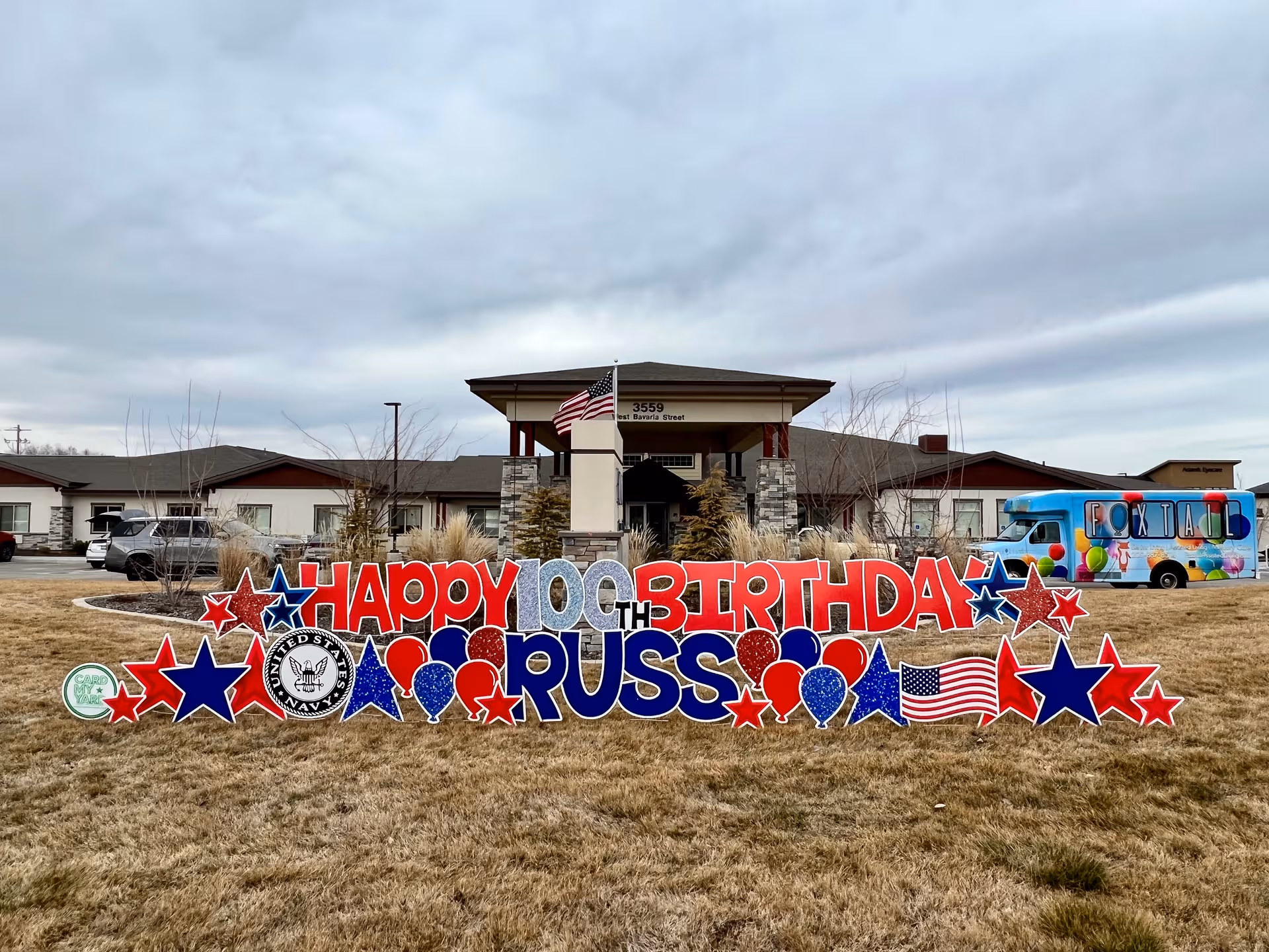 Front exterior of Foxtail Senior Living with a large colorful birthday display on the lawn.