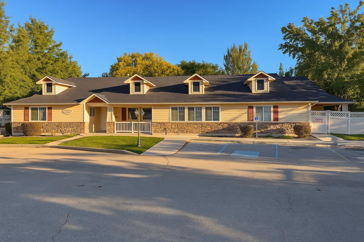 Ashley Manor Memory Care front exterior: single-story building with stone base, dormers, and parking.