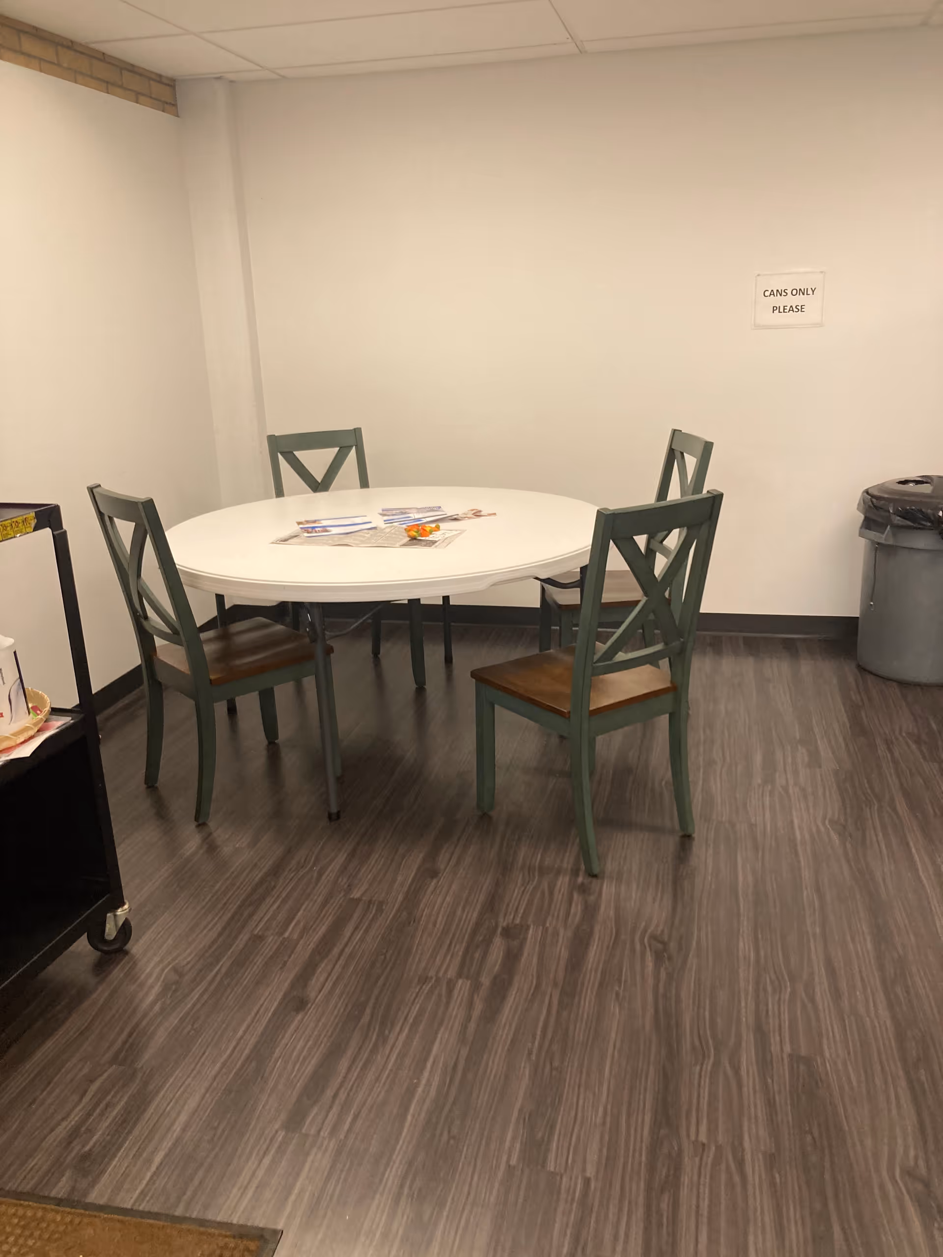 Small dining area with round white table and four green chairs.