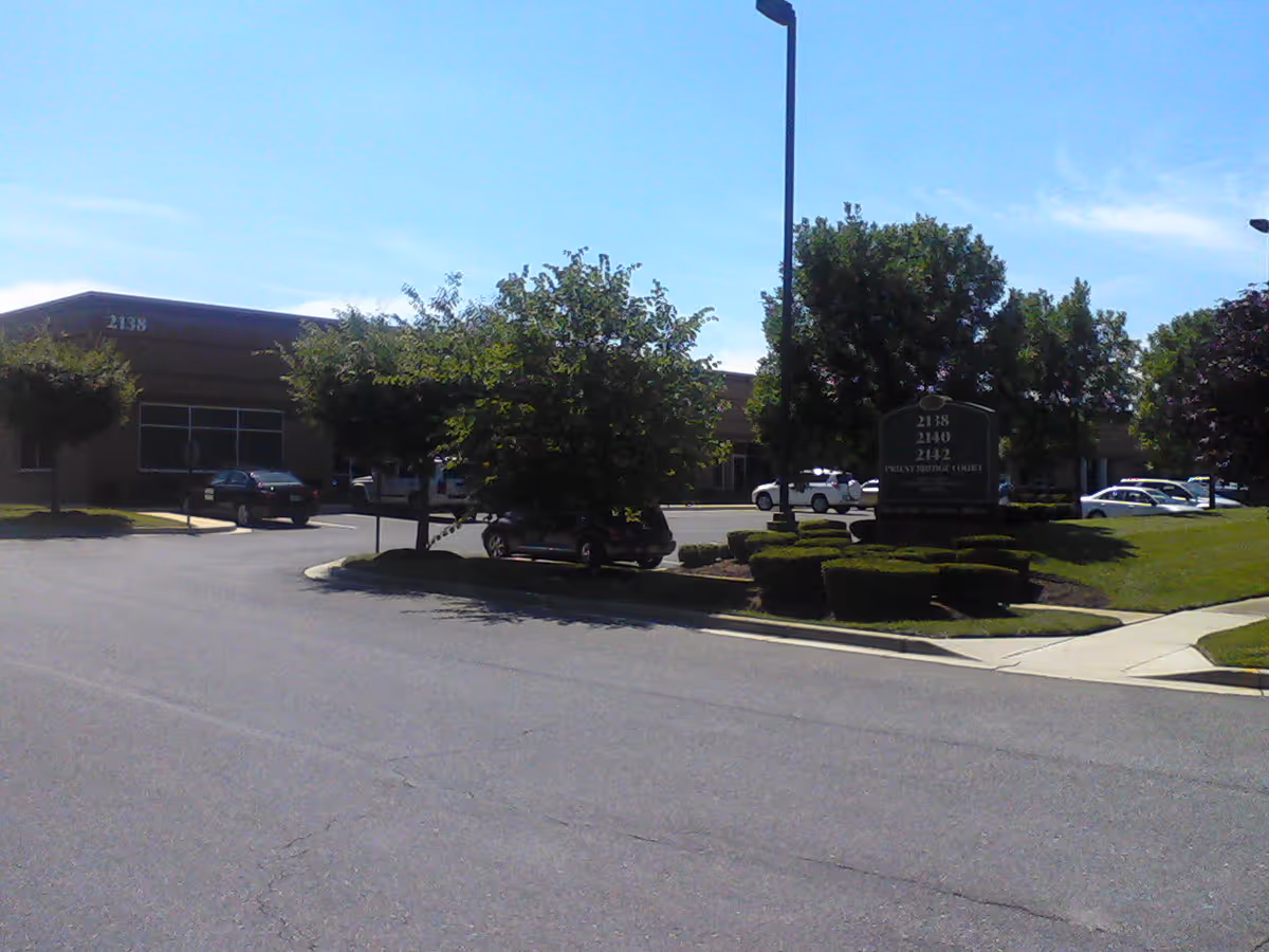Exterior view of a senior care facility with a sign and parked cars.