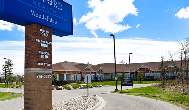Exterior view of Neilson Place senior living facility with sign and driveway.