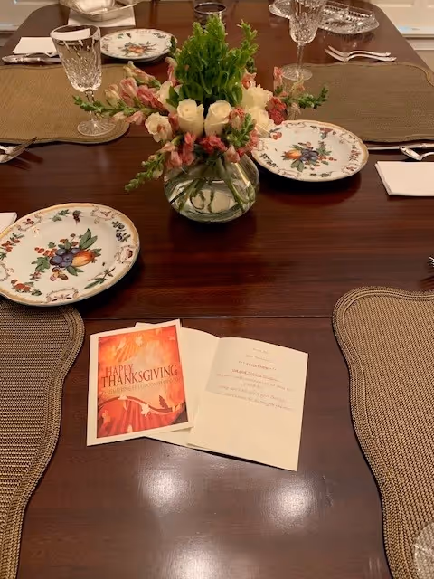 Dining table set with patterned plates, a floral centerpiece, and Thanksgiving cards.