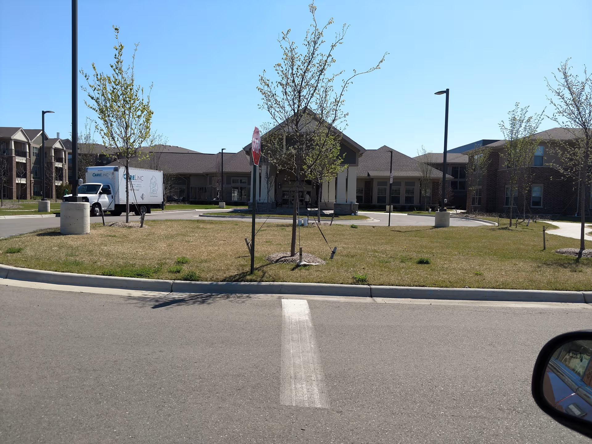 Exterior view of Cedarbrook of Northville with parking, trees, and a delivery truck.