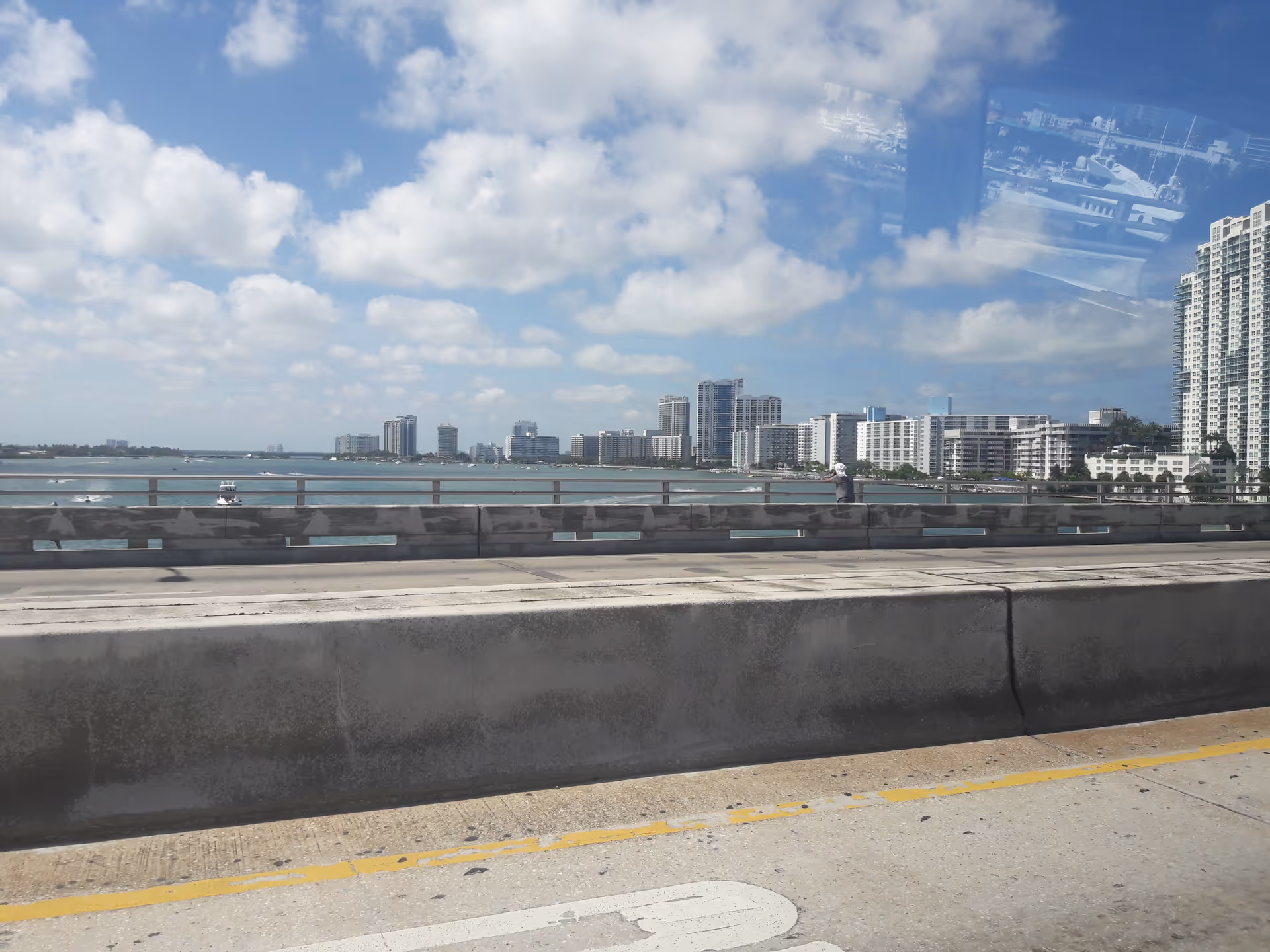 City skyline along the waterfront with a concrete seawall and metal railing in foreground