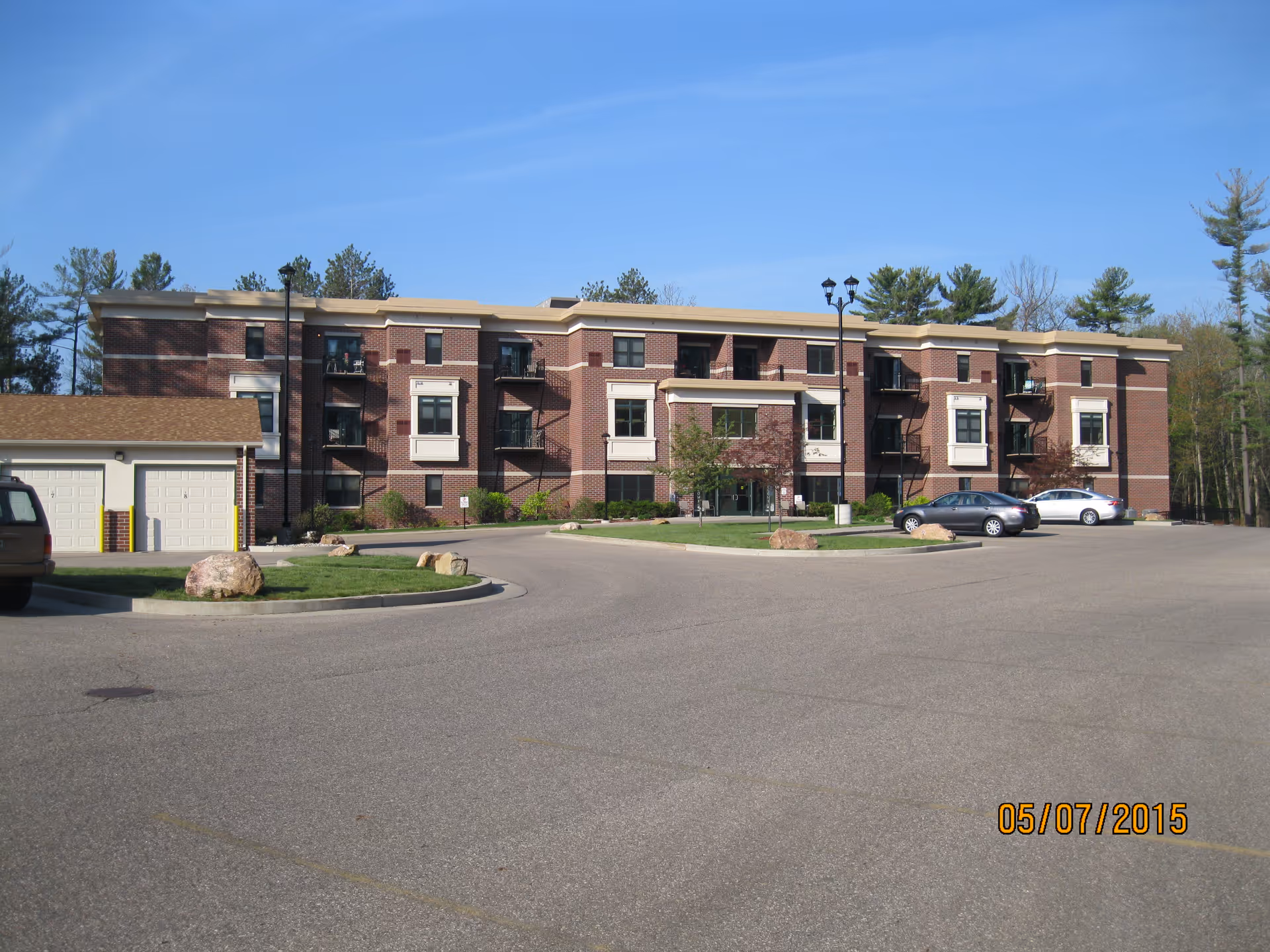 Exterior view of River View Lodge Assisted Living, brick building with circular driveway and cars.