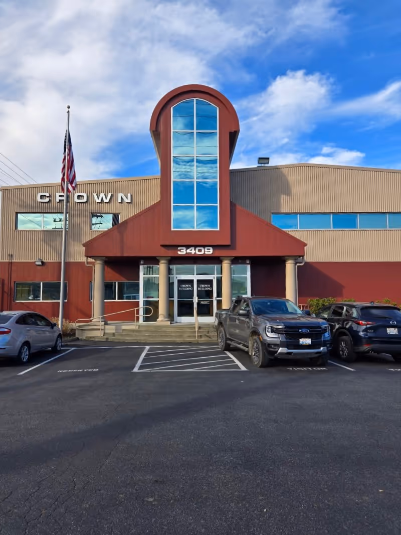 Exterior view of a red-front building entrance with pillars and parked cars.