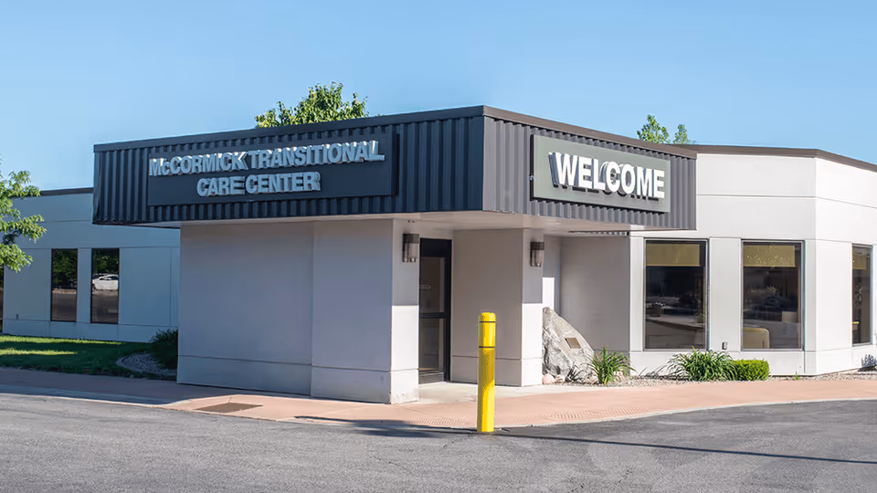 Exterior view of a care center entrance with a Welcome sign and McCormick Transitional Care Center.