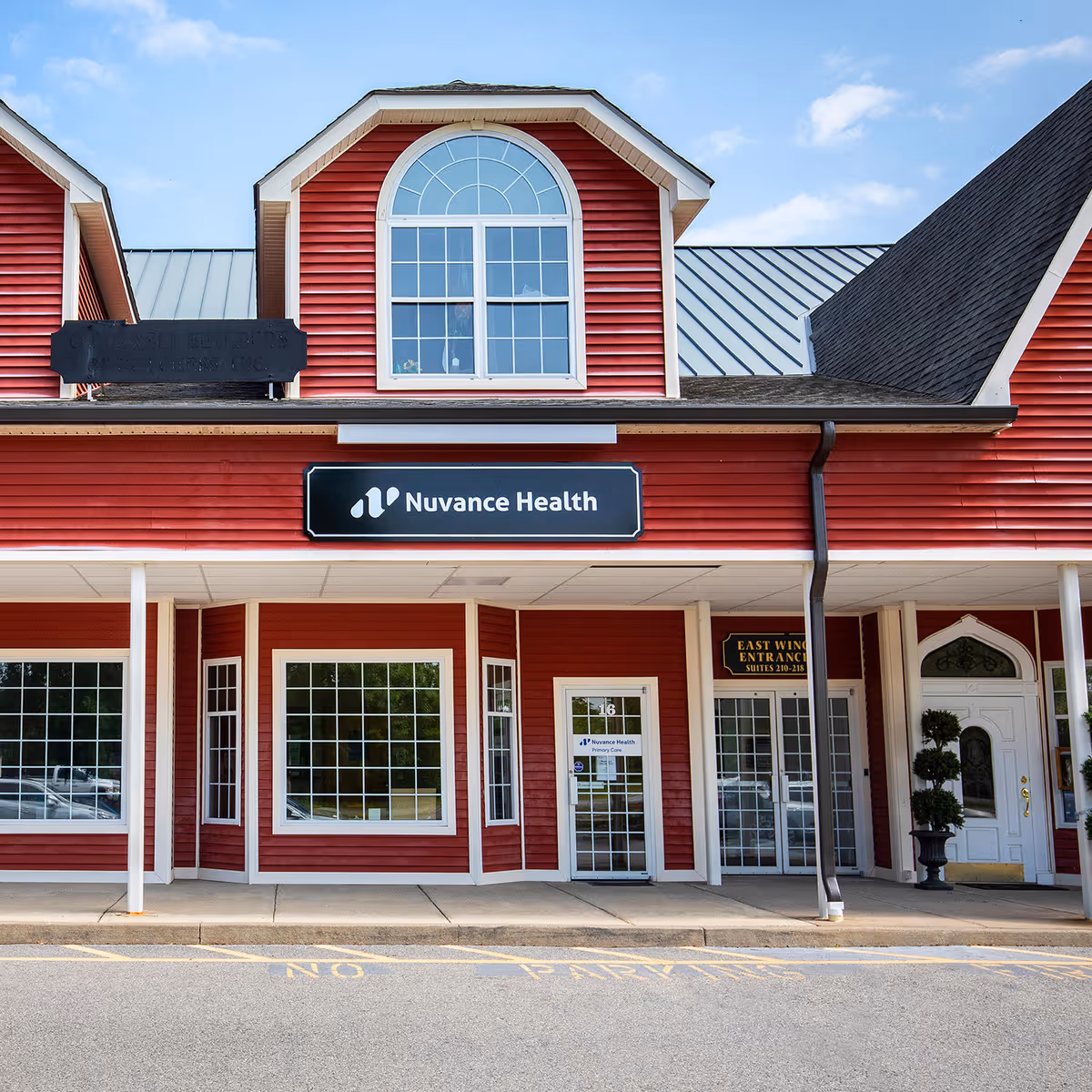 Red storefront medical clinic with Nuvance Health sign and arched front window.