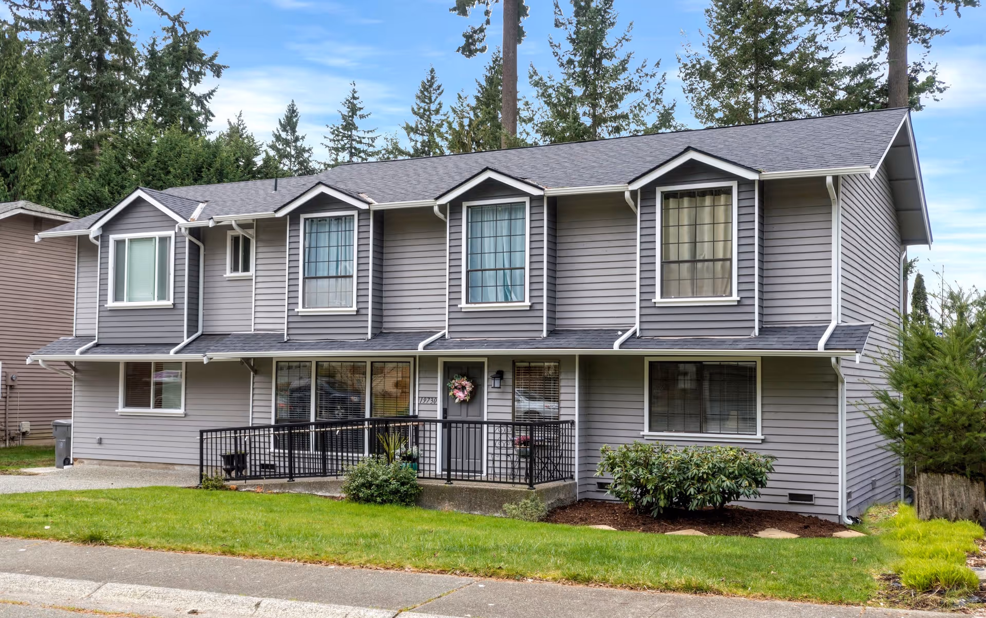 Two-story gray senior care home with a covered porch and landscaped front yard.