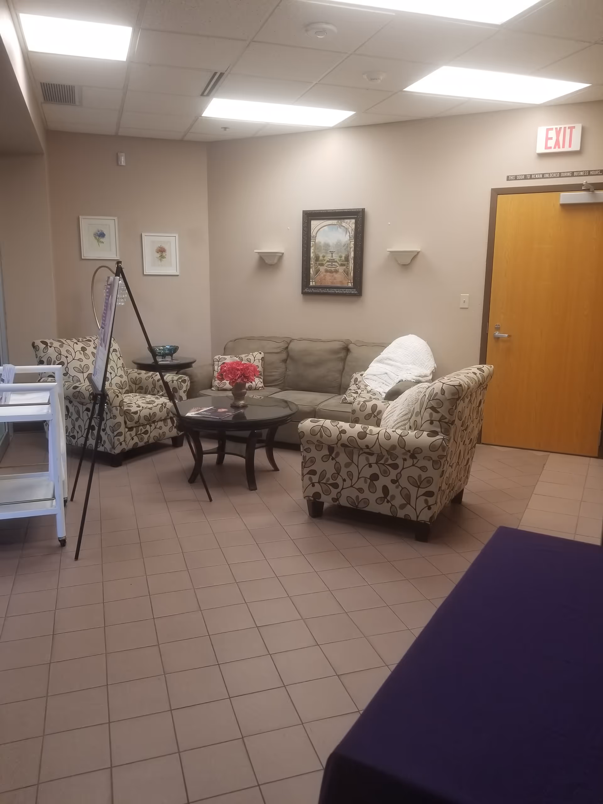 Indoor senior living lounge with patterned sofas, coffee table, and wall artwork.