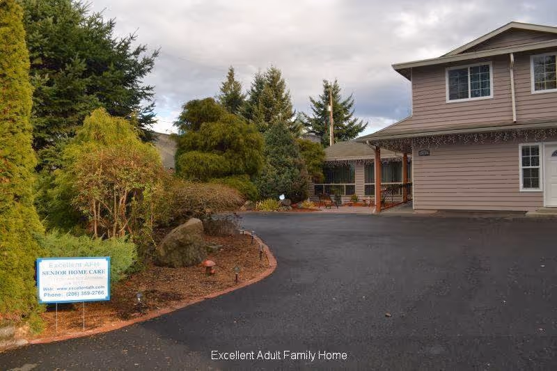 Exterior view of a senior home with a paved driveway, trees, and a covered entrance.
